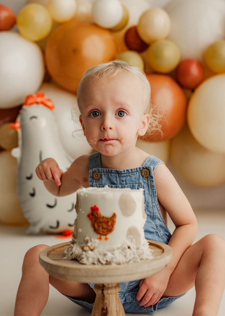 a toddler boy looking ready to sample his cake during a cake smash session