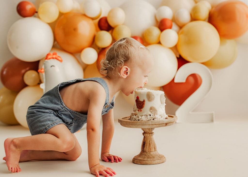 toddler taking a big bite out of his cake smash cake
