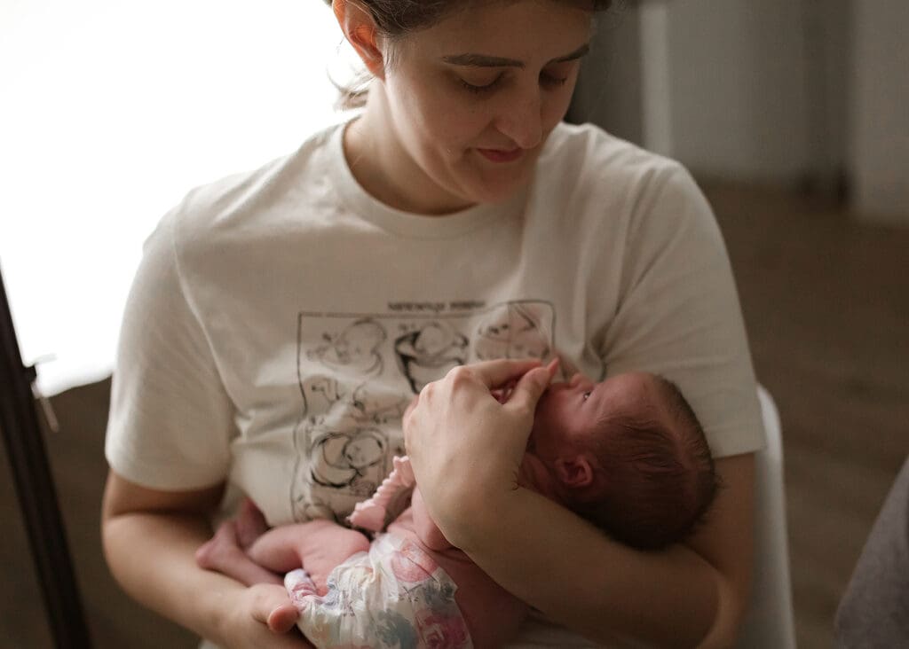 Photographer Jess Pearson holds newborn baby during a photography session