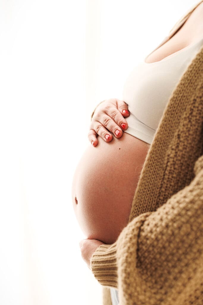 backlit images of pregnant mother holding her bump