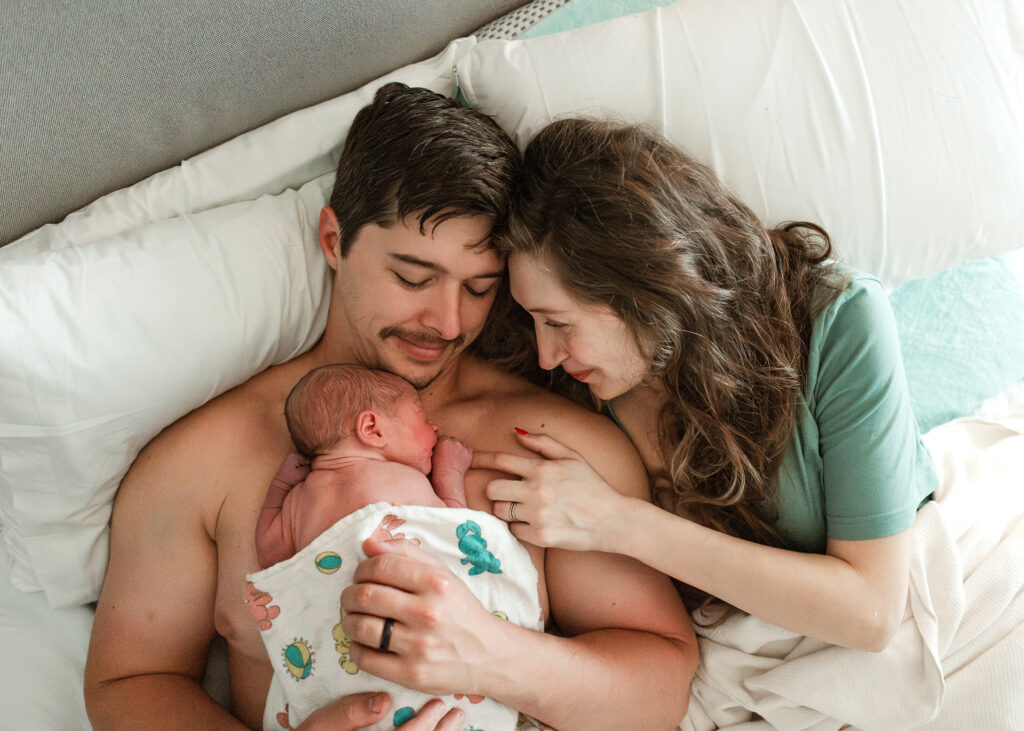 mom and her partner snuggling baby after a long, successful labor and delivery supported by their doula