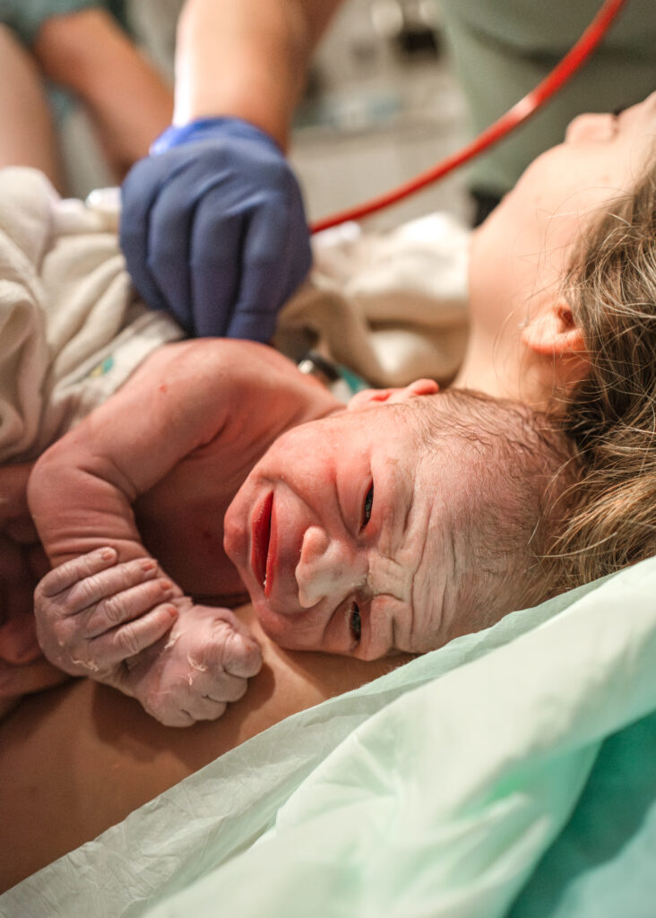 just born baby laying on mothers chest